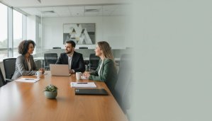 Recrutamento e seleção: entrevista em uma sala de reunião, com três pessoas conversando à mesa